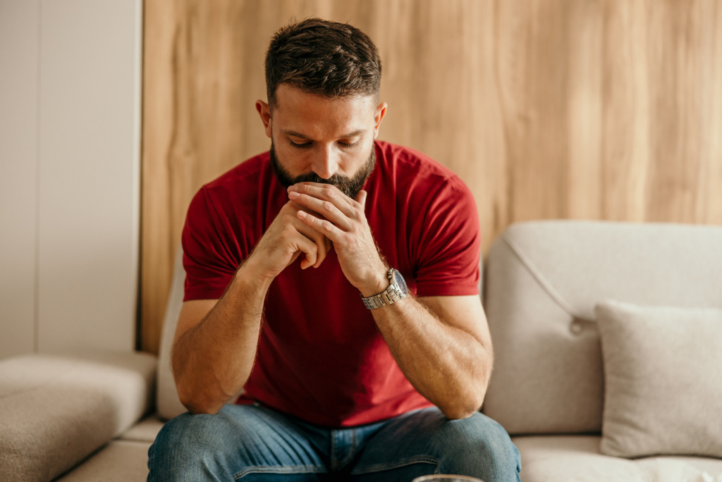 Man looking pensive while sitting on couch