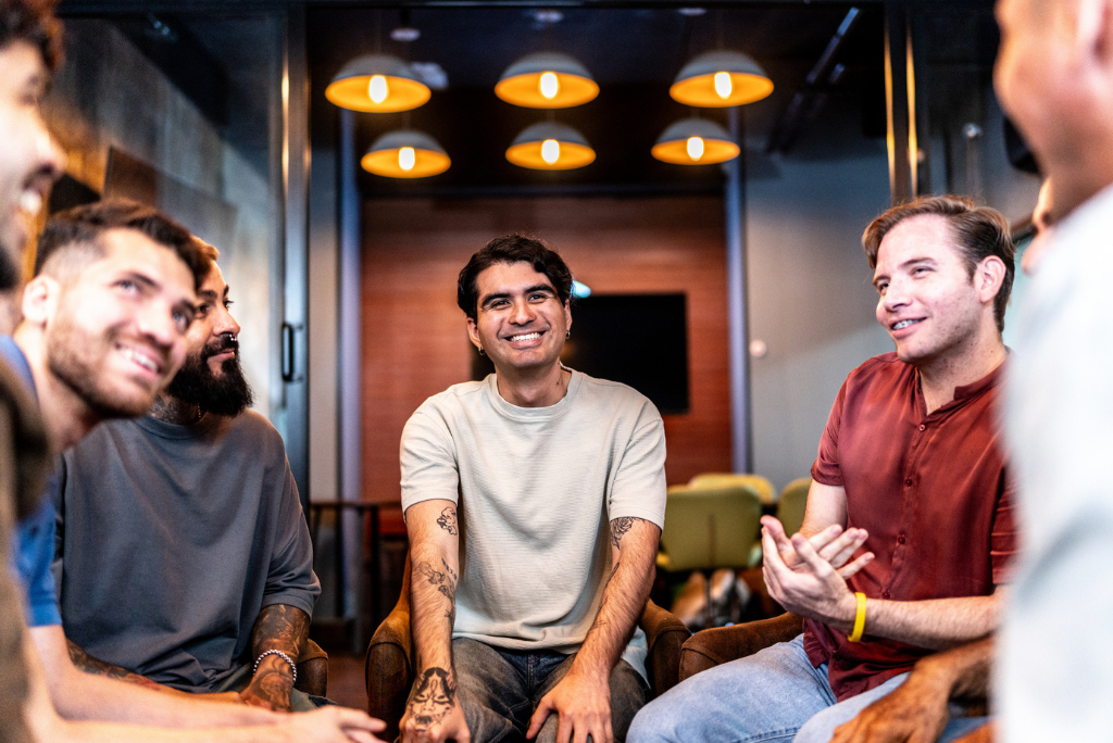Young men smiling while sitting a group